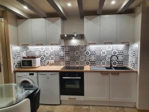 a kitchen with white cabinets and black and white tiles at Maisonette, Gîte de la Mère Nini in Saint-Laon +10 photos