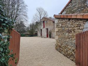 a stone building with a red door and a fence at Maisonette, Gîte de la Mère Nini in Saint-Laon