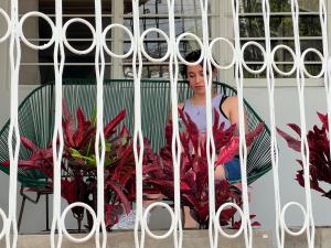 a woman is sitting behind a metal gate at Casa Epifania Miraflores hostel in Cali