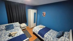 a bedroom with two beds and a blue wall at Totteham stadium in London