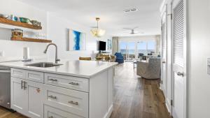a white kitchen with a sink and a living room at Blue Nine 2 in Panama City Beach