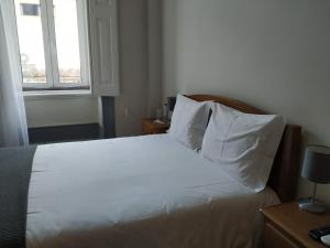 a bedroom with a bed with white sheets and a window at Casa Archie in São Pedro do Sul