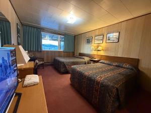 a hotel room with two beds and a flat screen tv at Airport Chalet in Whitehorse