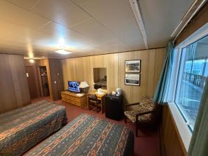 a hotel room with two beds and a desk and a window at Airport Chalet in Whitehorse