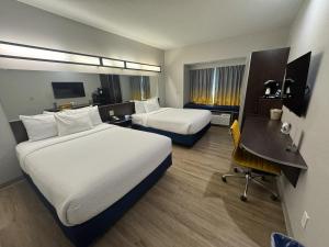 a hotel room with two beds and a desk at Microtel Inn & Suites by Wyndham Wheeling at The Highlands in Triadelphia