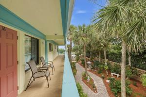 a porch of a house with chairs and palm trees at Sand Dune Shores in Palm Beach Shores