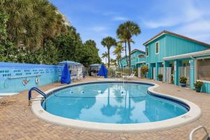 a large swimming pool with a blue house and palm trees at Sand Dune Shores in Palm Beach Shores