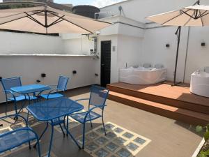 a patio with blue tables and chairs and a tub at Apartaestudios Zeni in Medellín