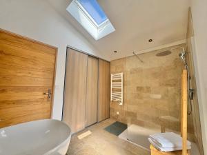 a bathroom with a tub and a shower and a skylight at Gîte du Colombier in Crestet +10 photos