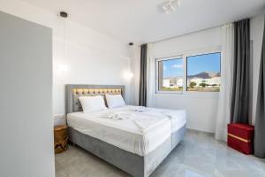 een witte slaapkamer met een groot bed en een raam bij Punta Mare Hotel in Karpathos