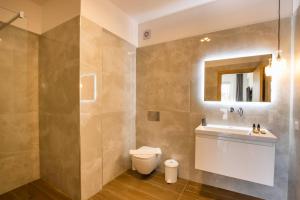 een badkamer met een wastafel, een toilet en een spiegel bij Punta Mare Hotel in Karpathos +30 foto's