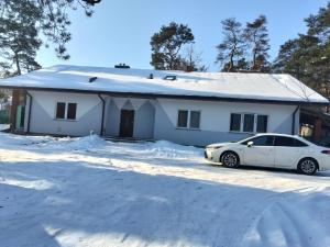 a white car parked in front of a house in the snow at Villa Varzob lll in Warsaw