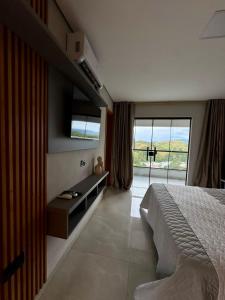 a bedroom with a large bed and a large window at Pousada Pôr do Sol in Cunha