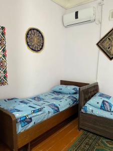 two twin beds in a room with a clock on the wall at Hotel Zukhritdin in Bukhara