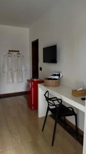 a room with a table and a chair and a tv at Suítes House Refúgio Fortim in Fortim