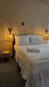 a bedroom with a white bed with towels on it at Suítes House Refúgio Fortim in Fortim