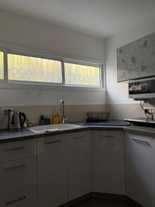 a kitchen with white cabinets and a sink and a window at The Urban Suite in Petaẖ Tiqwa +4 photos
