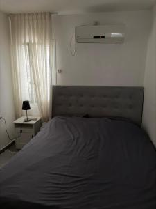a bedroom with a bed and a air conditioner at The Urban Suite in Petaẖ Tiqwa