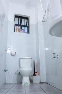 a white bathroom with a toilet and a sink at cozy 1bedroom mombasa bamburi near the beach with hot shower, Netflix, Secured parking 07&07 for 95 then 61to18 in Mombasa +14 photos