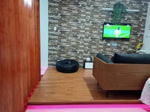 a room with a couch and a tv on a brick wall at Rye Lees Place in Bacolod