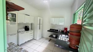 a kitchen with white cabinets and a refrigerator at Pousada Coxim in Coxim