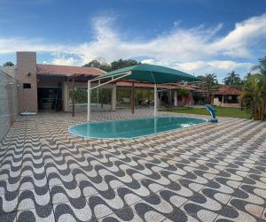 a swimming pool with a green umbrella next to a house at Pousada Coxim in Coxim