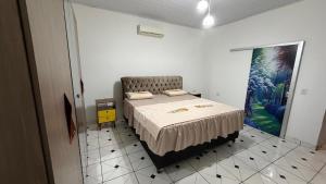a bedroom with a bed and a painting on the wall at Pousada Coxim in Coxim