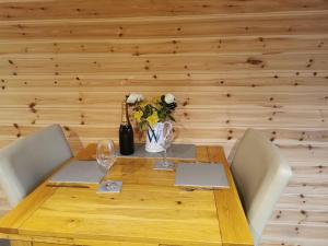 a wooden table with two chairs and a vase of flowers at Thelmas Lodge in Llanelli +4 photos