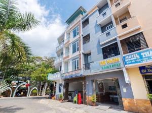 a large building on a street with a palm tree at The Warm khách sạn bãi sau giá rẻ in Vung Tau
