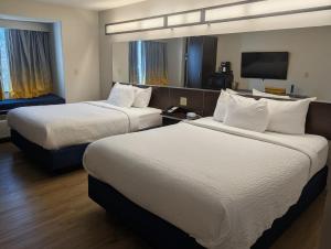 a hotel room with two beds and a flat screen tv at Microtel Inn & Suites by Wyndham Wheeling at The Highlands in Triadelphia +21 photos