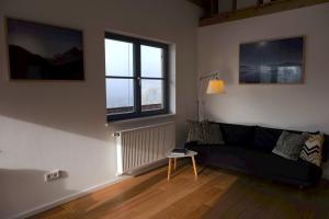 a living room with a black couch and two windows at Ein Haus am Berg in Marquartstein