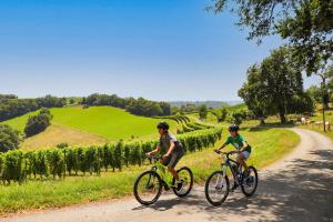 two people riding bikes down a dirt road at Maison Tournesol Massages Pau Jurançon in Gan