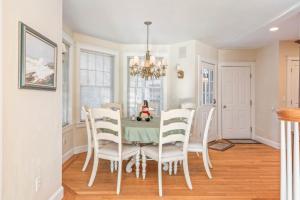 a dining room with a table and white chairs at Town & Tide Home for 8 in Kennebunkport