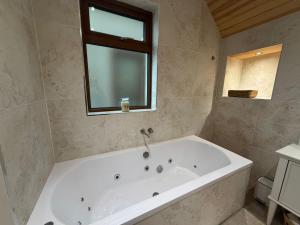 a white bath tub in a bathroom with a window at Sessaigh lake studio in Dunfanaghy