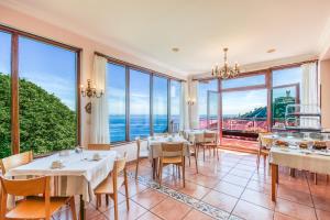 a dining room with tables and chairs and large windows at Hotel Leku Eder in San Sebastián