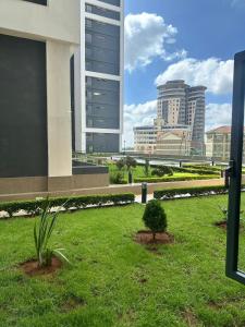 a park with a tree in the grass with buildings at BlaQ Homes in Kanga