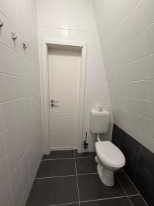 a bathroom with a white toilet and a door at SchaeBu! 7 Apartment Work and Travel am Altmarkt in Cottbus
