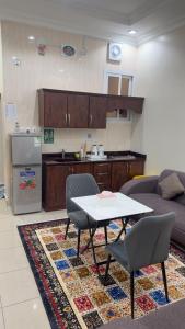 a living room with a table and a kitchen at Najmat Sabbabah Furnished Units in Hail