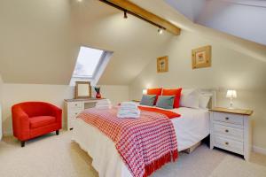 a attic bedroom with a bed and a red chair at 3 Bed in Machynlleth oc-bow91 in Penegoes