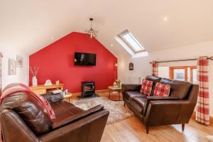 a living room with leather furniture and a red wall at 2 Bed in Lixwm oc-bow179 in Halkyn