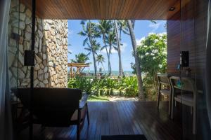 a room with a table and chairs and palm trees at Pedras Do Patacho Hotel Boutique Experience in Pôrto de Pedras