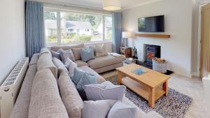 a living room with a large couch and a fireplace at 3 Bed in Llanbedrog oc-llynor in Llanbedrog