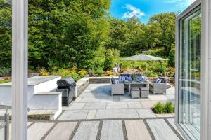 a patio with a table and chairs and an umbrella at 3 Bed in Llanbedrog oc-llynor in Llanbedrog