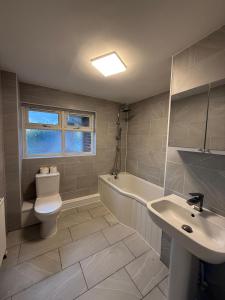 a bathroom with a toilet and a sink and a tub at Exquisite King-sized Bedroom - Free Parking in Dartford