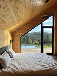 a large bed in a room with a large window at Carpathic Chalet in Comandău