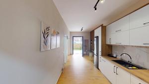 a kitchen with white cabinets and a long hallway at Vila MUJE in Belsh