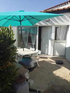 a patio with a table and an umbrella at RESIDENCE du NEPTUNE in Saint-Cyprien-Plage
