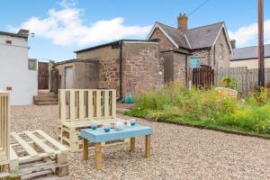 a garden with two wooden benches and a table at 1 Bed in Berwick-upon-Tweed oc-a32026 in Kyloe