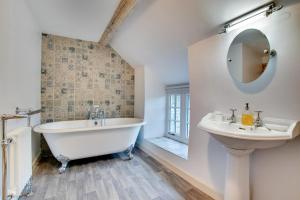 a bathroom with a tub and a sink and a mirror at 4 Bed in Ruthin oc-bow136 in Gwyddelwern +33 photos