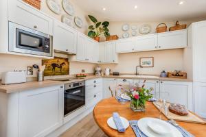 a kitchen with white cabinets and a wooden table at 1 Bed in Ashton oc-p30484 in Ashton
